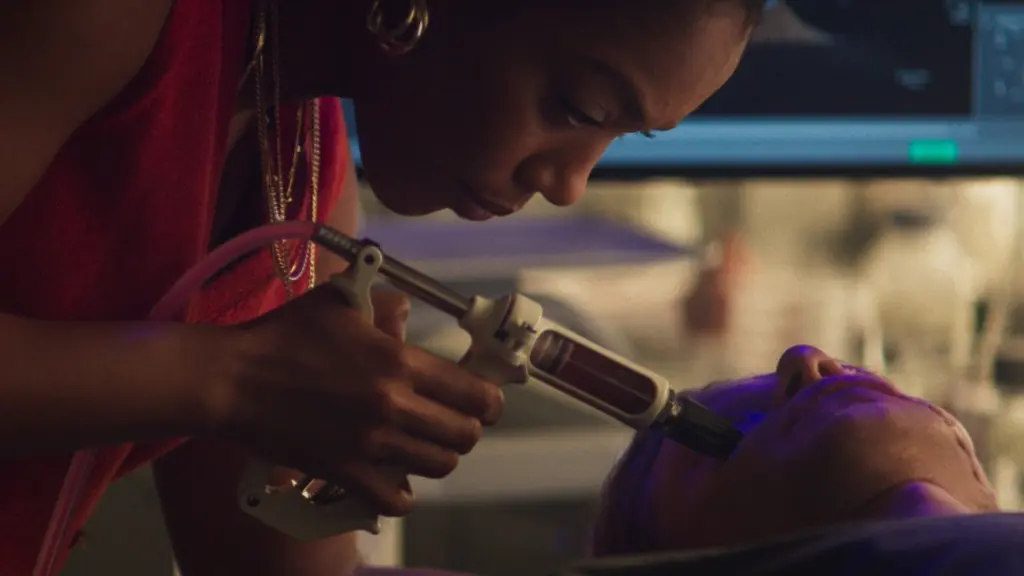 Naomi Ackie as Dr. Caitlyn Corr injects experimental stem cells into Matt Hagen's face in DC's CLAYFACE.